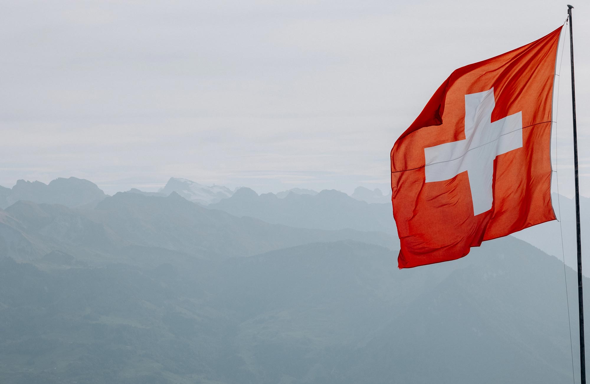 Schweizer Flagge vor Alpenkulisse – Symbol für regionale Nähe und schweizweite Aktenvernichtung mit REISSWOLF