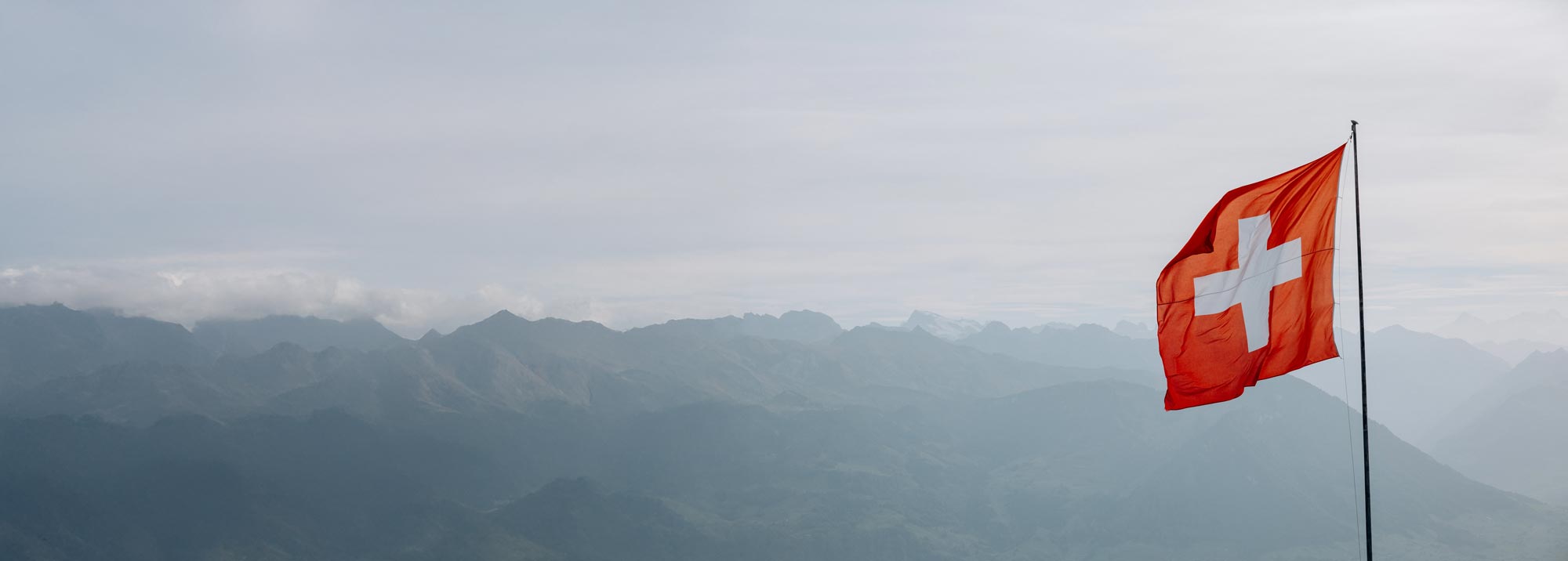 Schweizer Flagge vor Alpenpanorama – Symbol für regionale Präsenz und Datenschutz „made in Switzerland“