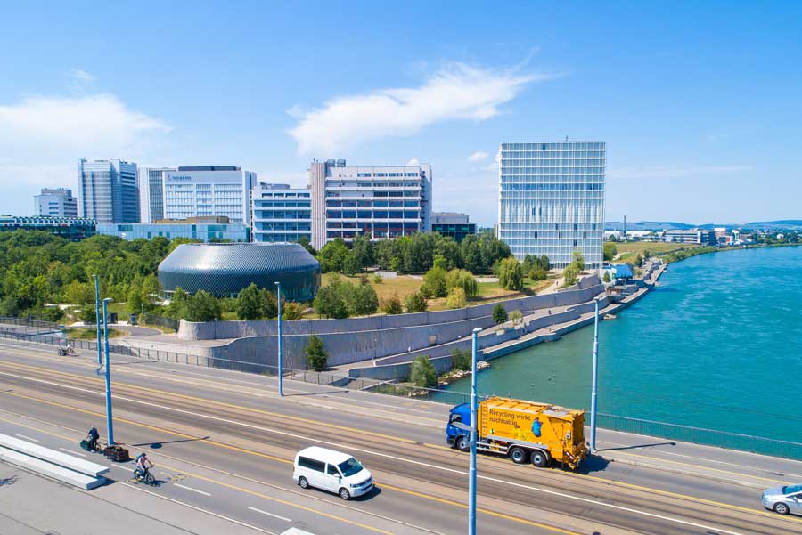 Paprec Schweiz – Entsorgungsfahrzeug am Rhein in Basel vor moderner Firmenkulisse